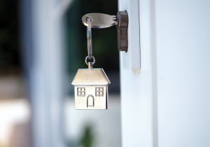 key in unlocked and open door; keychain shaped like house