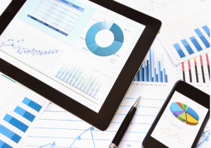 digital tablet and smartphone with generic data charts, and paper generic data charts in background